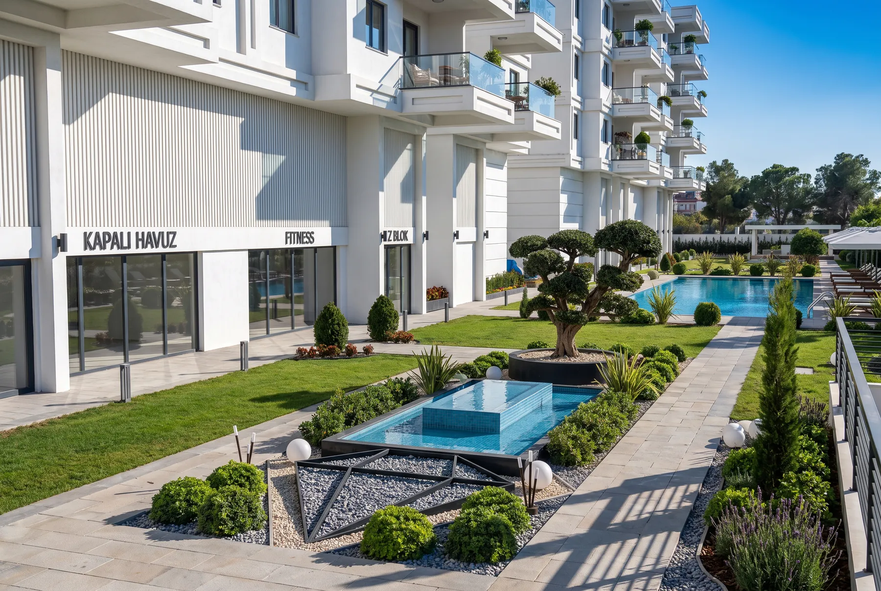 Karat Alyans kapalı havuz ve fitness cephesi, süs havuzlu peyzaj ve arkada açık havuz
